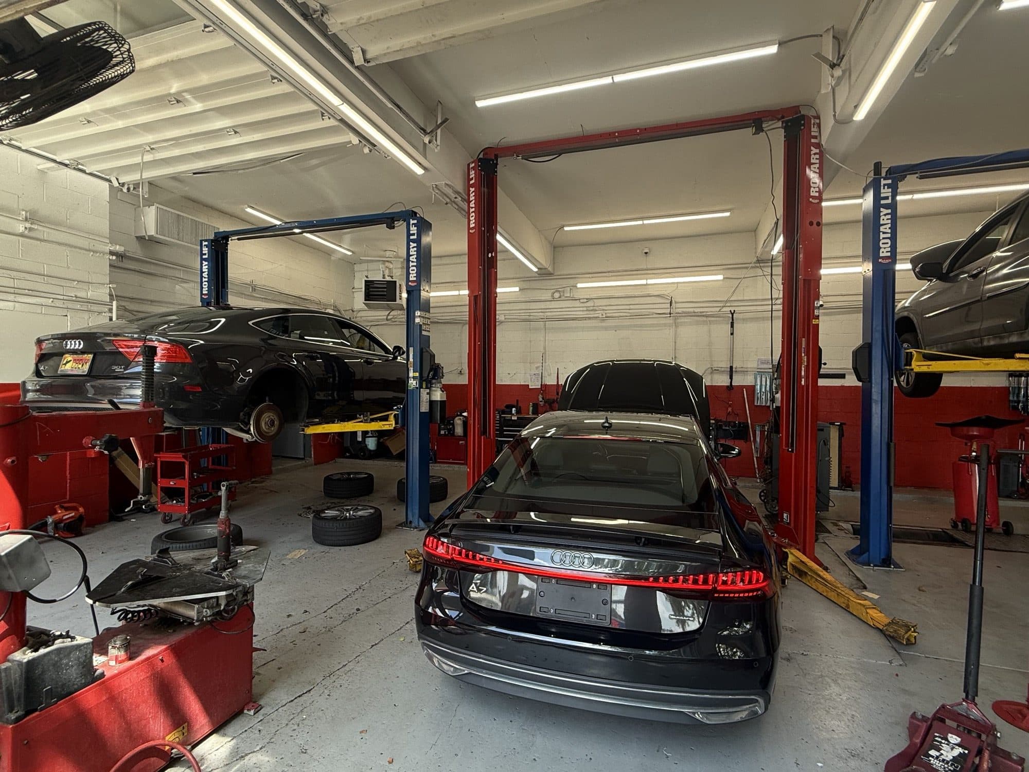 Inside the TAB Motors Arlington workshop: an Audi raised on a Rotary lift, another on the bay floor, in a clean, well-lit shop