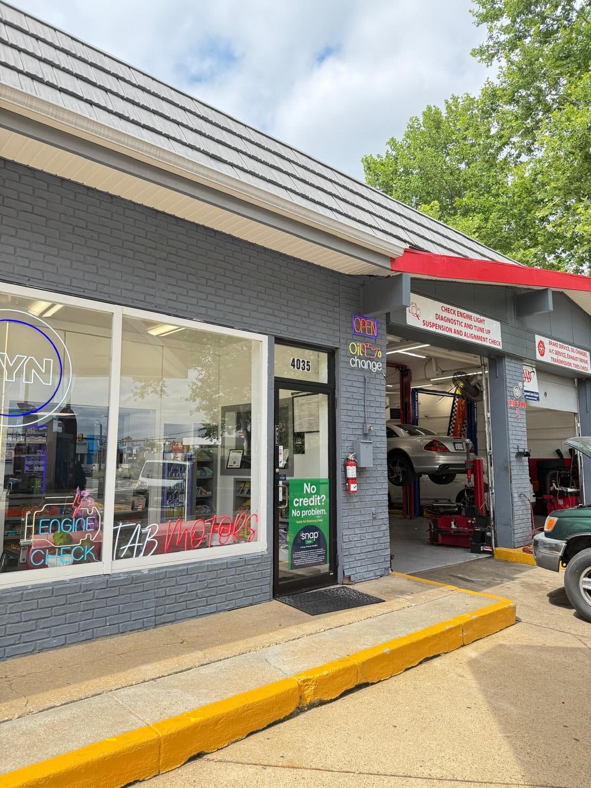 The TAB Motors Arlington front entrance at 4035 Langston Blvd, with the TAB Motors window sign, an open service bay and a car on the lift